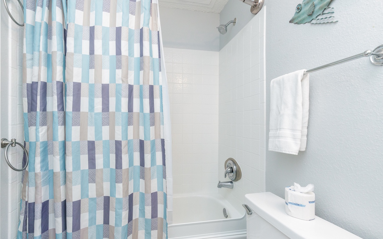 Step into your clean, bright bathroom with ocean-themed touches and fluffy towels ready for your relaxing soak.