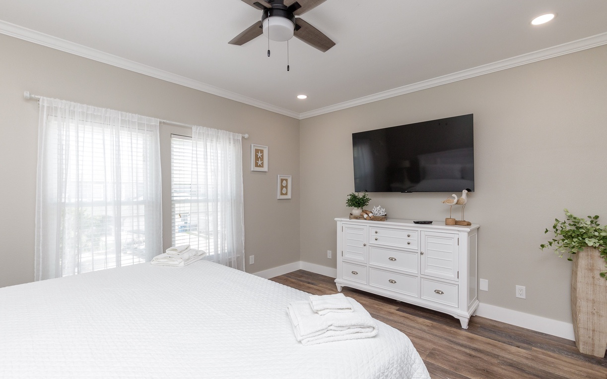 Unwind in your serene bedroom with crisp linens, gentle ceiling fan breeze, and entertainment at your fingertips.