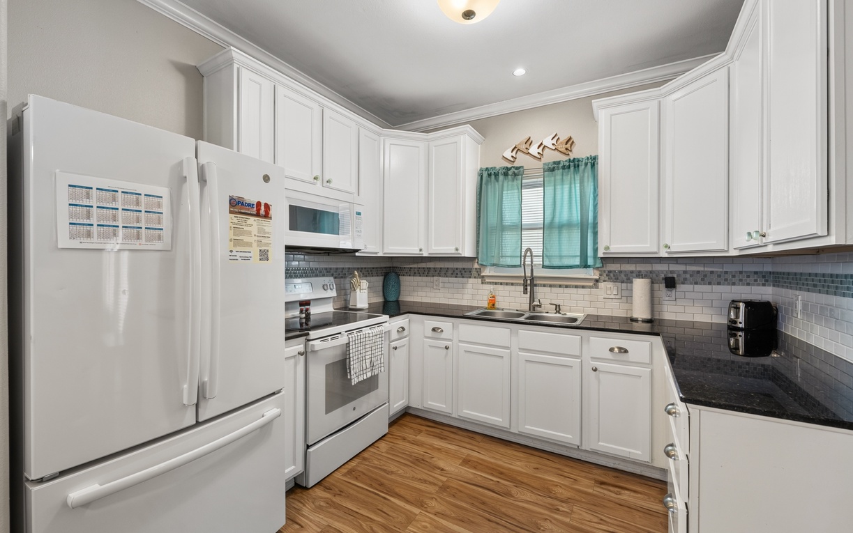 Your fully equipped kitchen awaits, featuring sleek white cabinetry, granite countertops, and everything you need to prepare meals in style during your stay.
