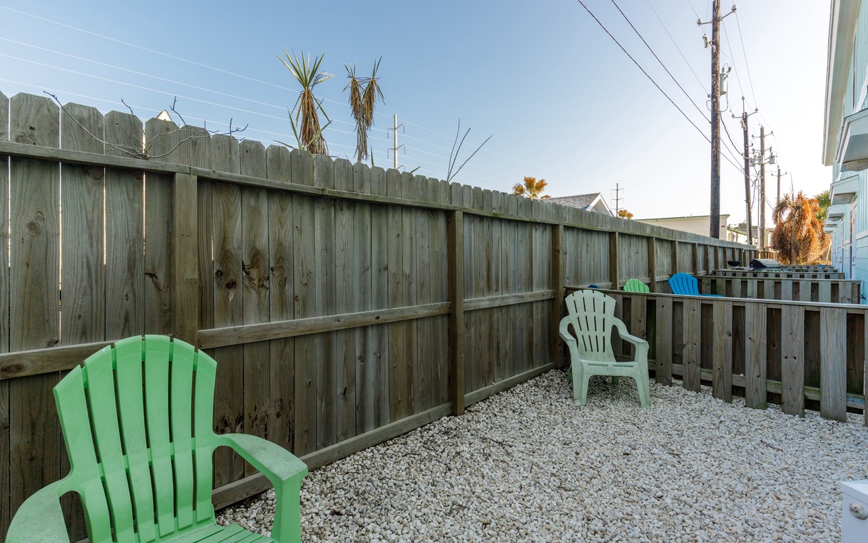 Step onto your private patio where colorful Adirondack chairs await your morning coffee or evening relaxation in this peaceful outdoor space.