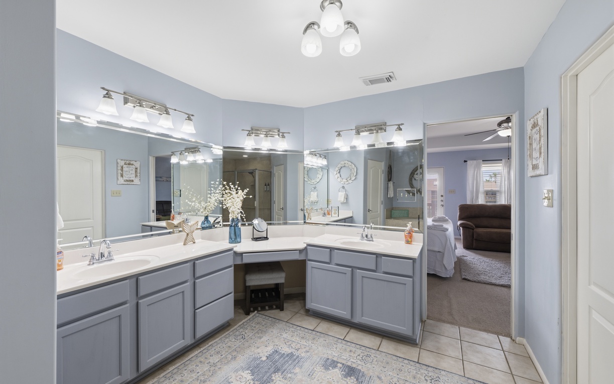 Step into your private bathroom retreat—featuring dual vanities with ample counter space, bright Hollywood lighting, and a thoughtfully designed corner layout that balances style with comfort.