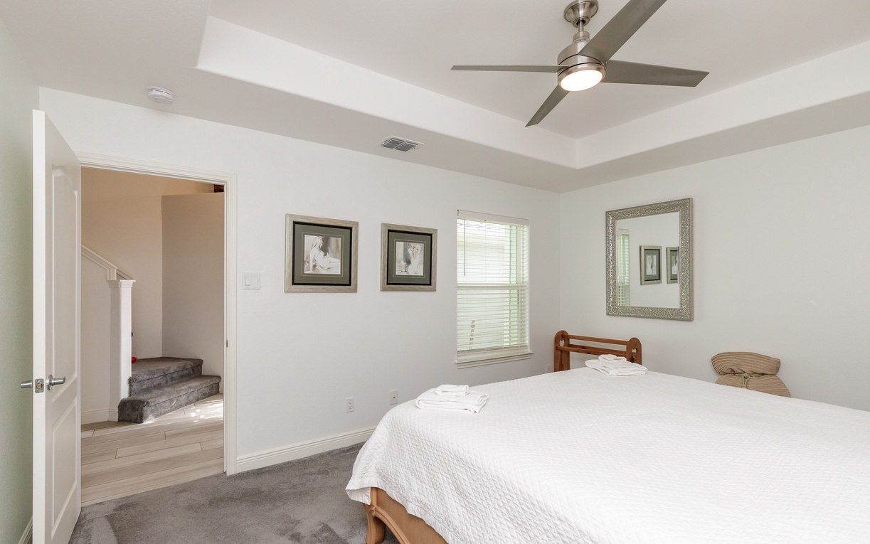 Drift off peacefully in this bright, airy bedroom where crisp linens and gentle ceiling fan breezes ensure restful nights.