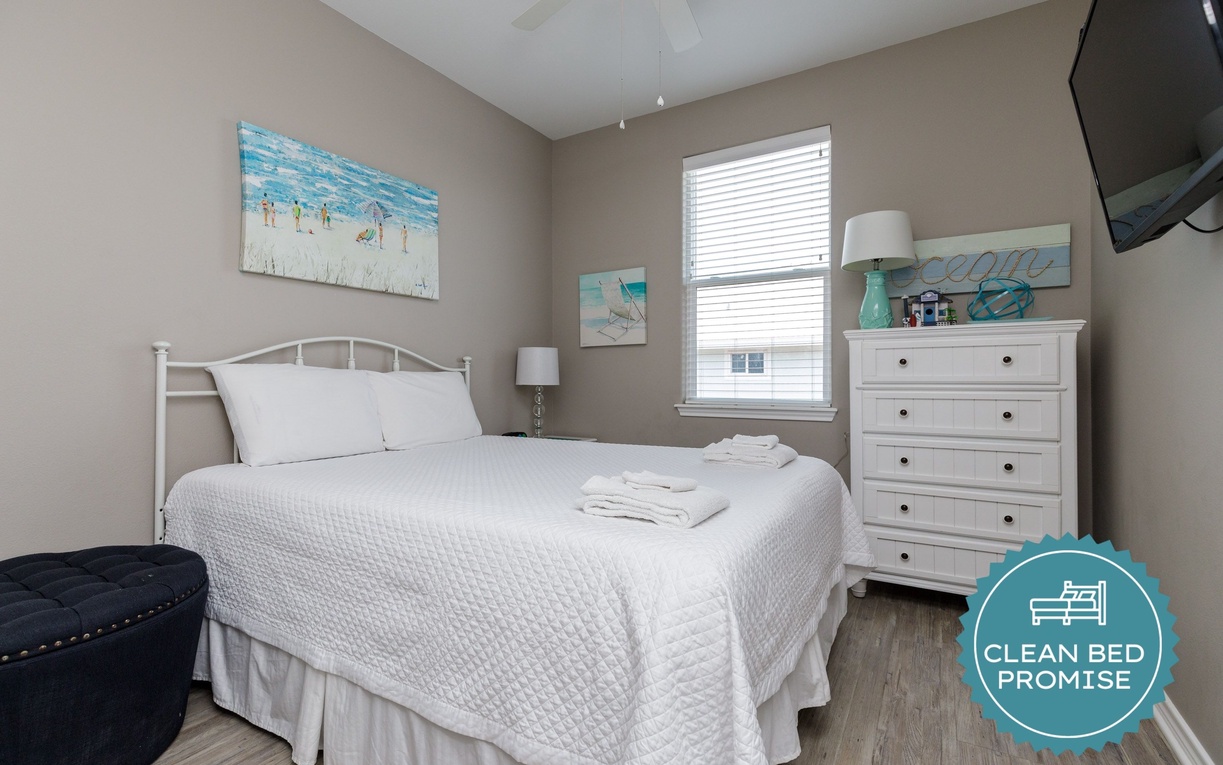 Drift off in your cozy bedroom with coastal artwork, fresh linens, and a wall-mounted TV for relaxation.