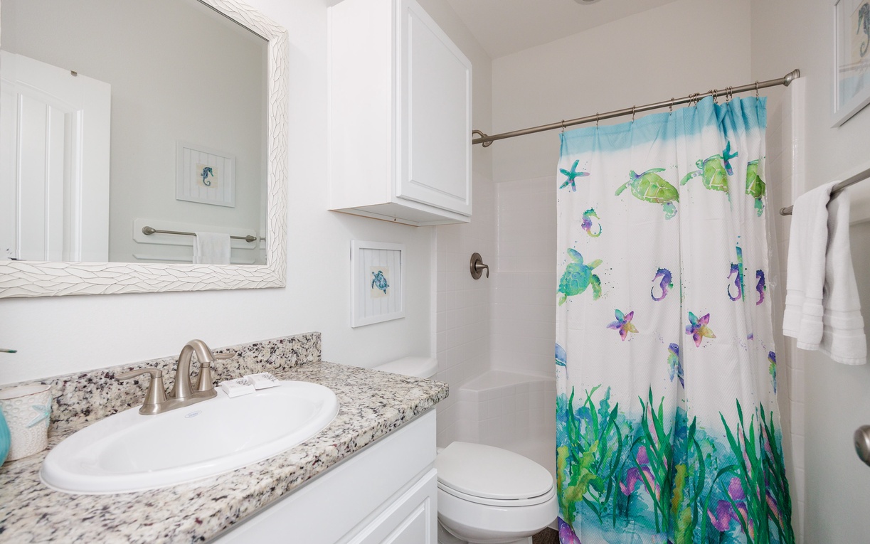 Refresh in your bright bathroom with granite counters and cheerful ocean-themed shower curtain that brings coastal charm to your daily routine.