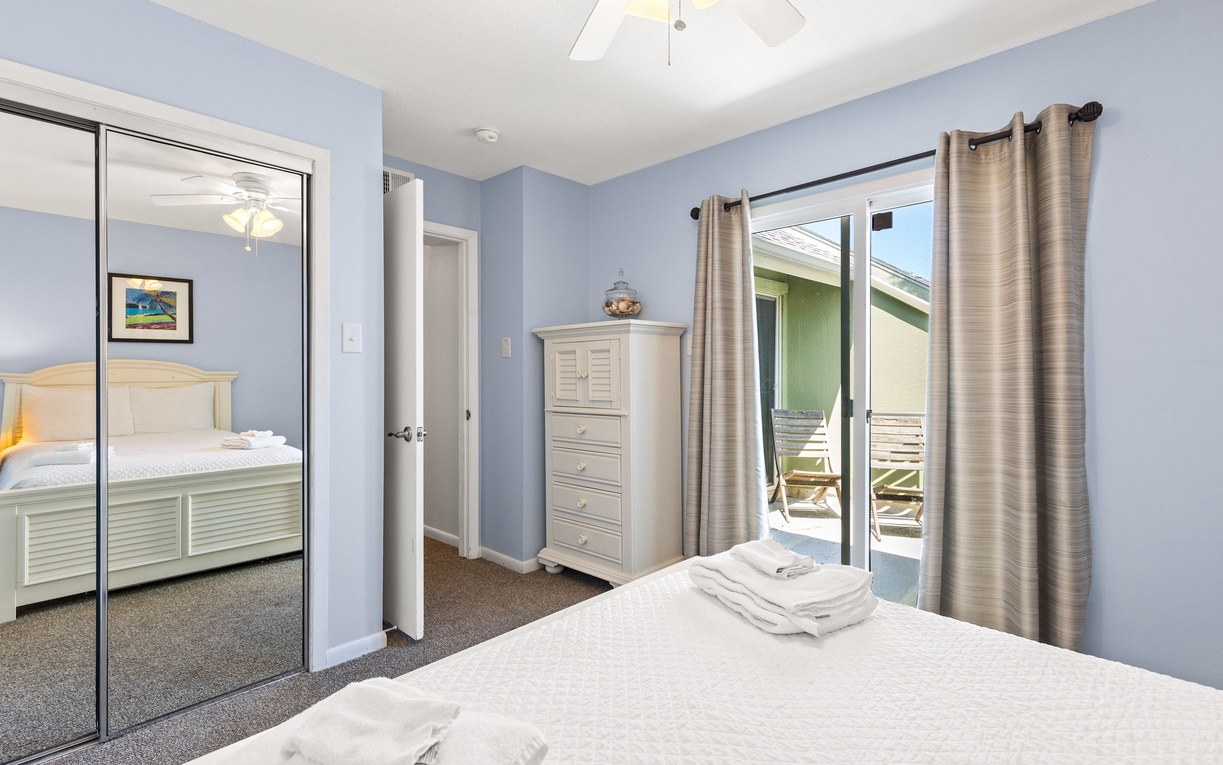 Your peaceful bedroom features soft blue walls, mirrored closets, and patio access for morning coffee outdoors.