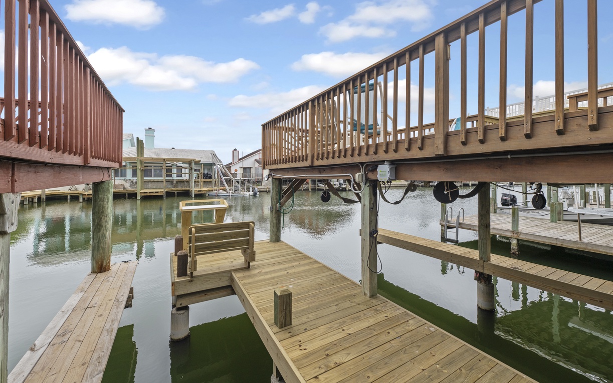 Waterfront community with private boat docks, elevated walkways, and canal access surrounded by coastal homes.