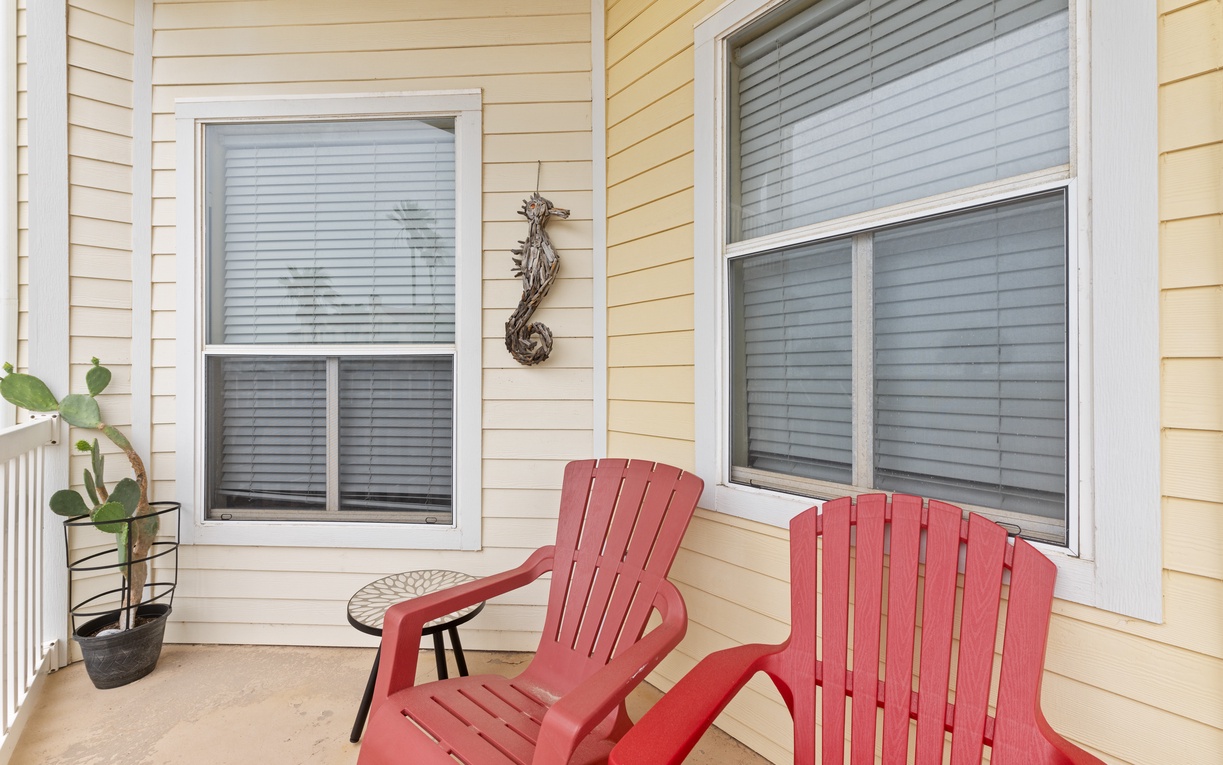 Settle into your private porch with cheerful red Adirondack chairs, perfect for morning coffee and peaceful moments.