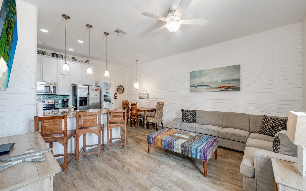Your open-concept living space features comfortable seating, a fully equipped kitchen, and coastal-inspired touches that create the perfect home base.