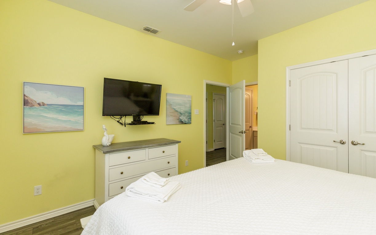 Wake up in your bright, cheerful bedroom featuring coastal artwork, modern amenities, and plenty of storage for a relaxing stay.