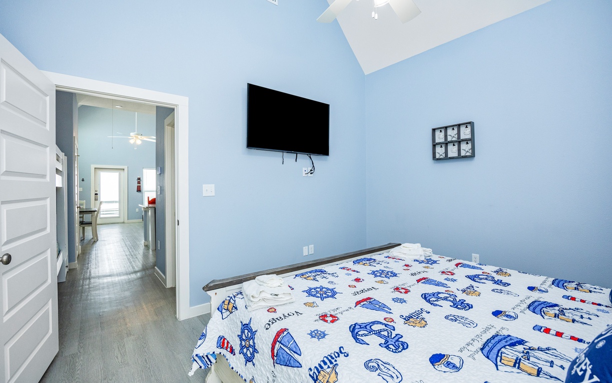 Drift off in your nautical-themed bedroom with soaring vaulted ceilings, wall-mounted TV for cozy movie nights, and cheerful blue walls that create a serene coastal escape.