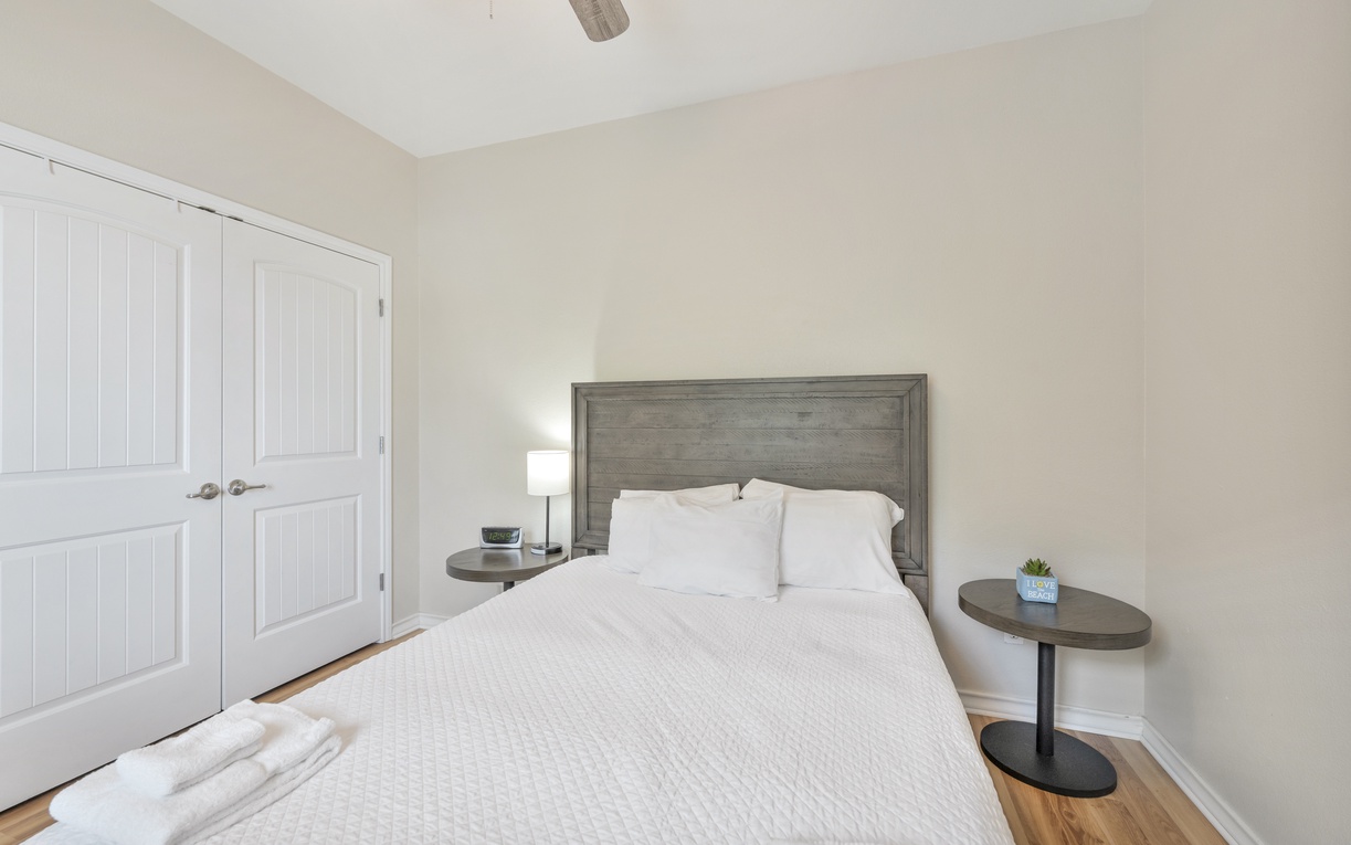 Slip into crisp linens and let the coastal breeze from the ceiling fan lull you to sleep in this serene bedroom retreat.