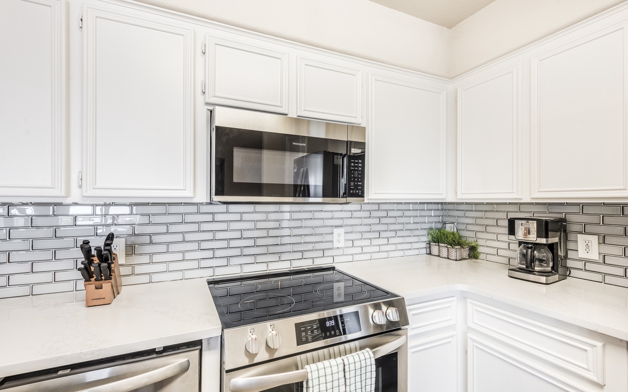 Your fully-equipped kitchen features gleaming white cabinets, stainless appliances, and elegant subway tile—perfect for morning coffee or preparing your favorite meals.