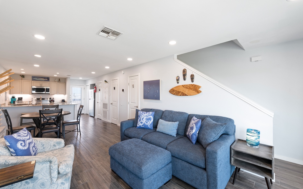 Step into your breezy coastal haven, where open-concept living blends comfort and style. Sink into the plush blue sectional, whip up fresh meals in your modern kitchen, or gather around the dining table—all within one light-filled space.