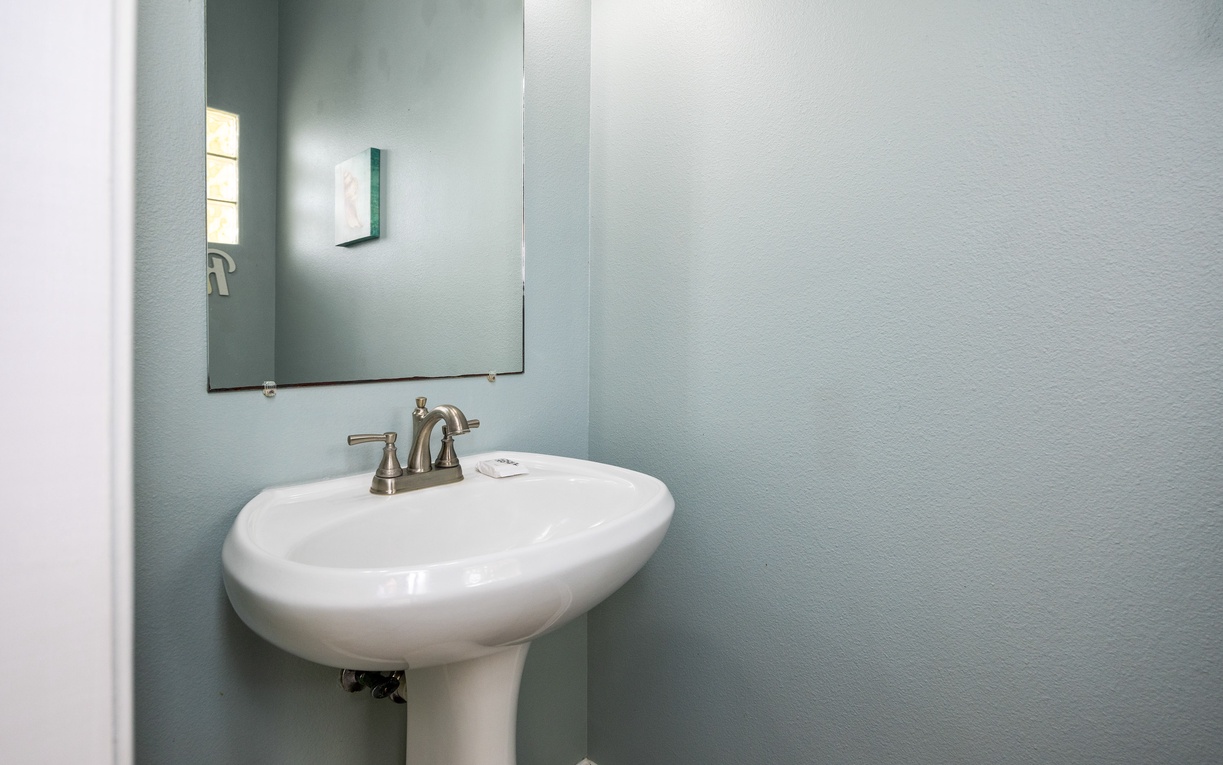 Your private powder room features a pristine pedestal sink and elegant mirror, creating a clean, refreshing space for quick touch-ups.