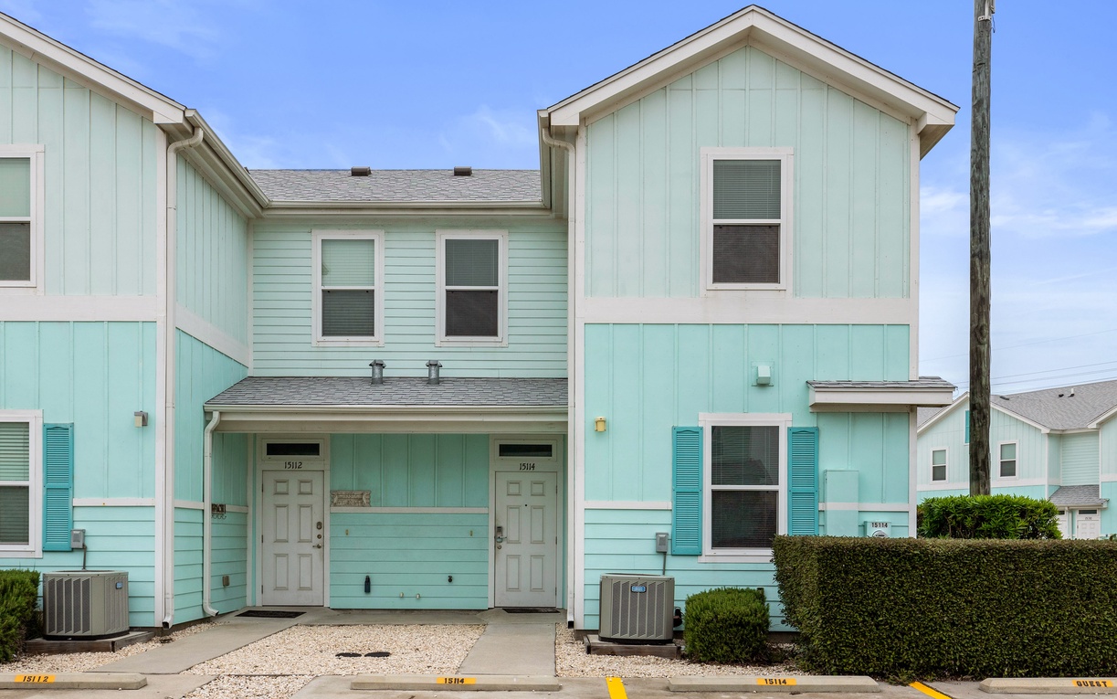 Charming coastal-style townhome with soft mint siding and convenient parking awaits your beach getaway.