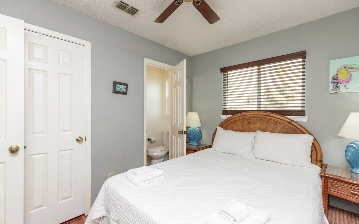 Sink into crisp white linens in your peaceful bedroom, where gentle breezes from the ceiling fan keep you cool and comfortable.