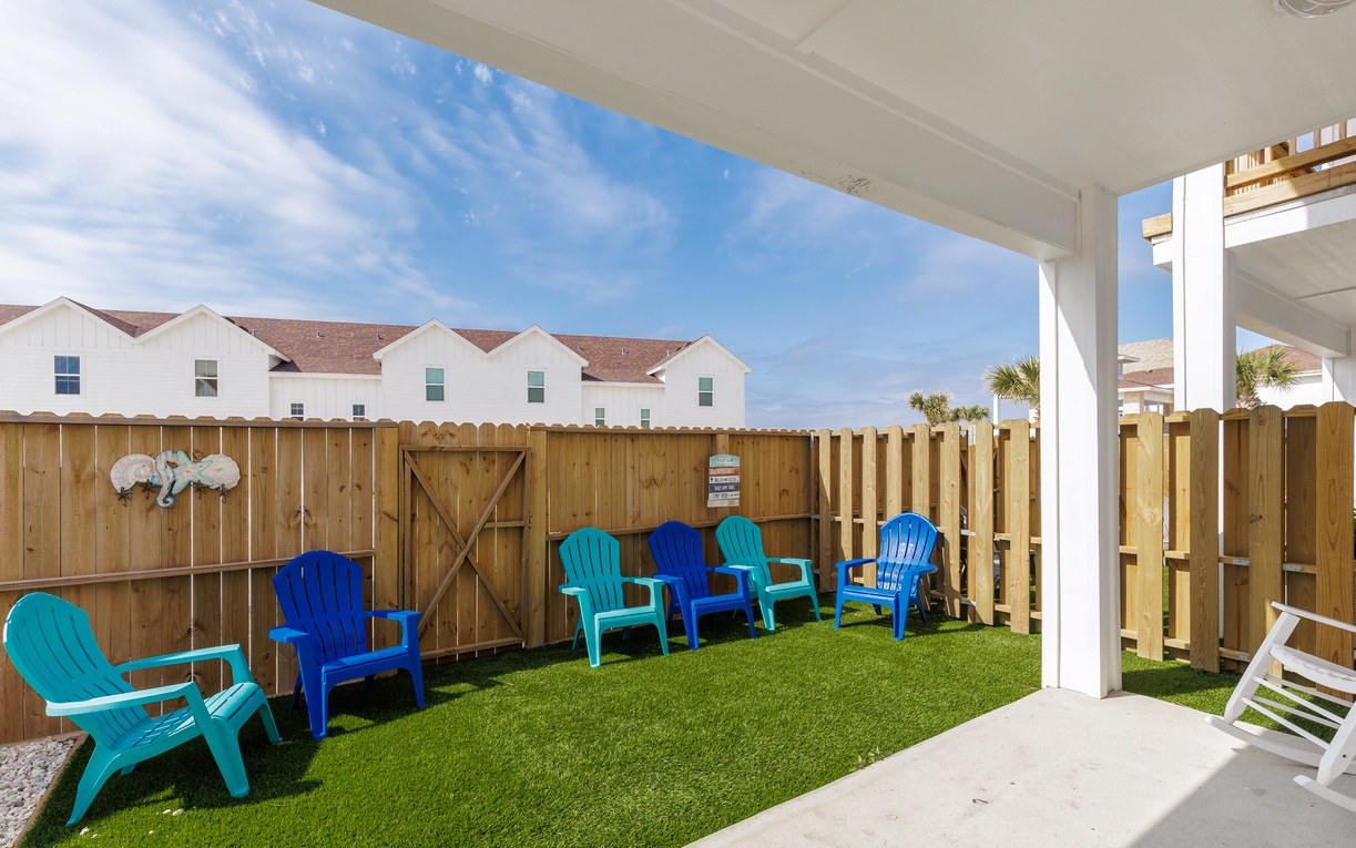 Gather your group on the spacious covered patio with colorful Adirondack chairs arranged on lush artificial turf for effortless outdoor relaxation.