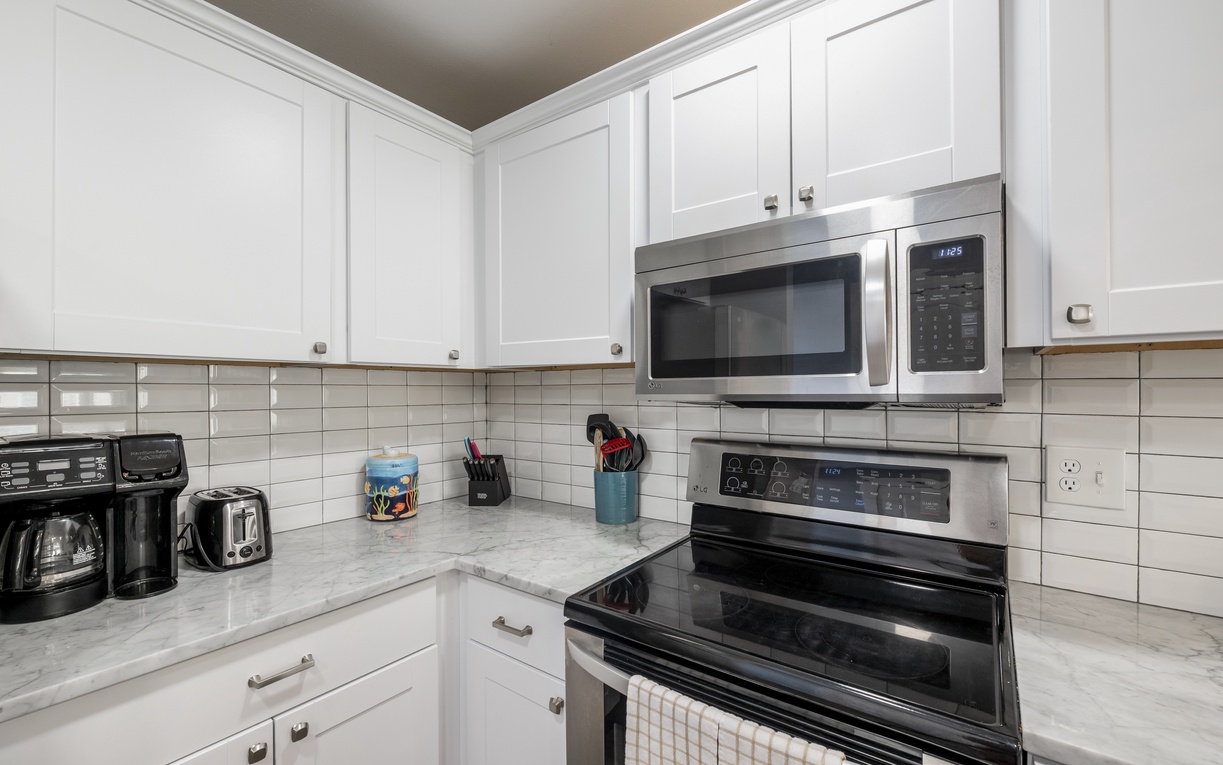 Your fully equipped kitchen awaits with gleaming stainless steel appliances, pristine white cabinets, and marble countertops perfect for preparing meals.