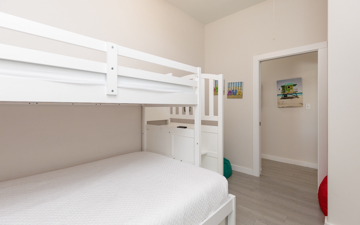Your kids will love this cheerful bunk bed room with plenty of space to play and colorful beach artwork brightening the walls.