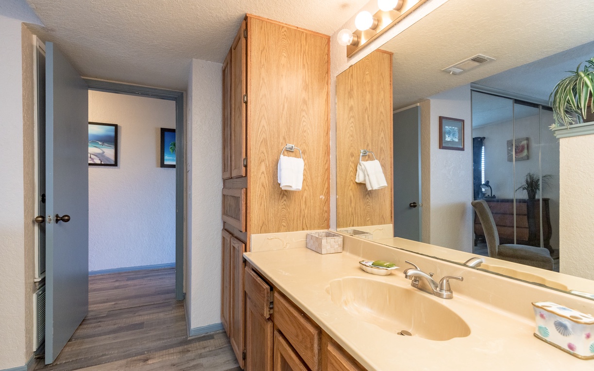 Your spacious bathroom features warm wood cabinets, elegant marble countertops, and plenty of storage to keep your essentials organized during your stay.