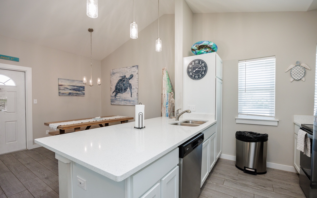 Your coastal-themed kitchen invites culinary adventures with modern appliances, quartz counters, and charming sea turtle artwork creating a serene cooking atmosphere.