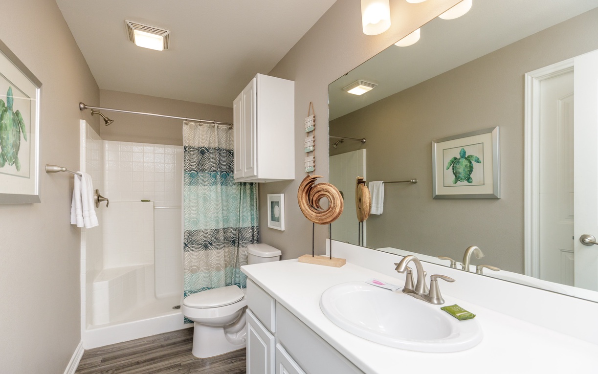 Refresh in your coastal-themed bathroom with turtle art, marble counters, and a tiled shower—your private spa retreat.