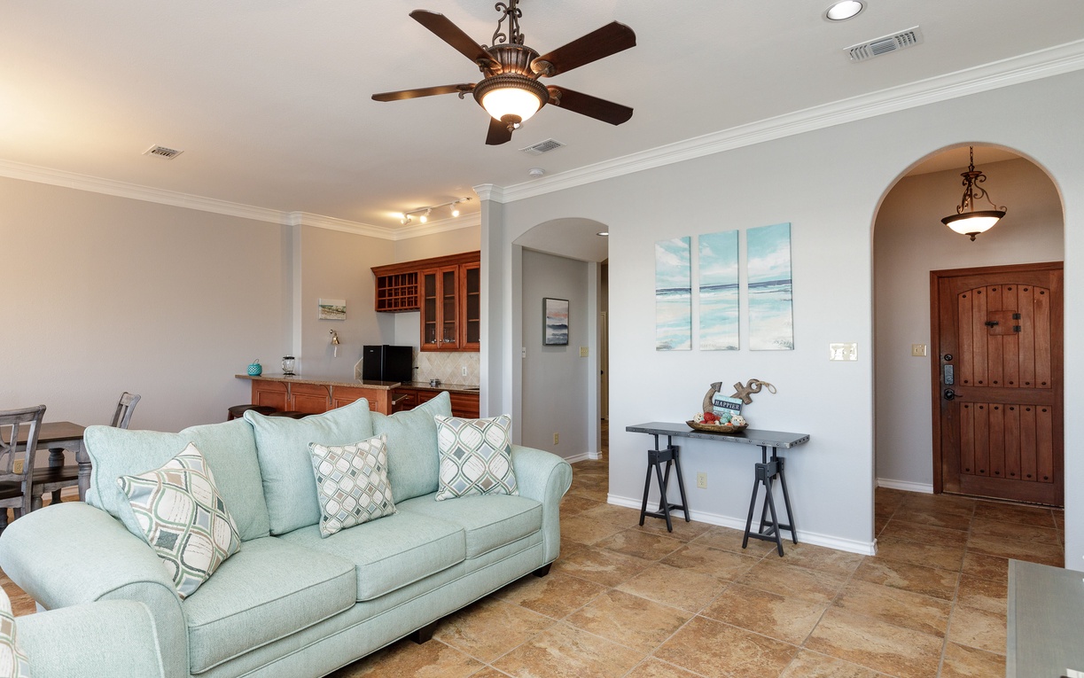 Relax in your open-concept living space with coastal decor, ceiling fan, and kitchen connection for effortless vacation living.