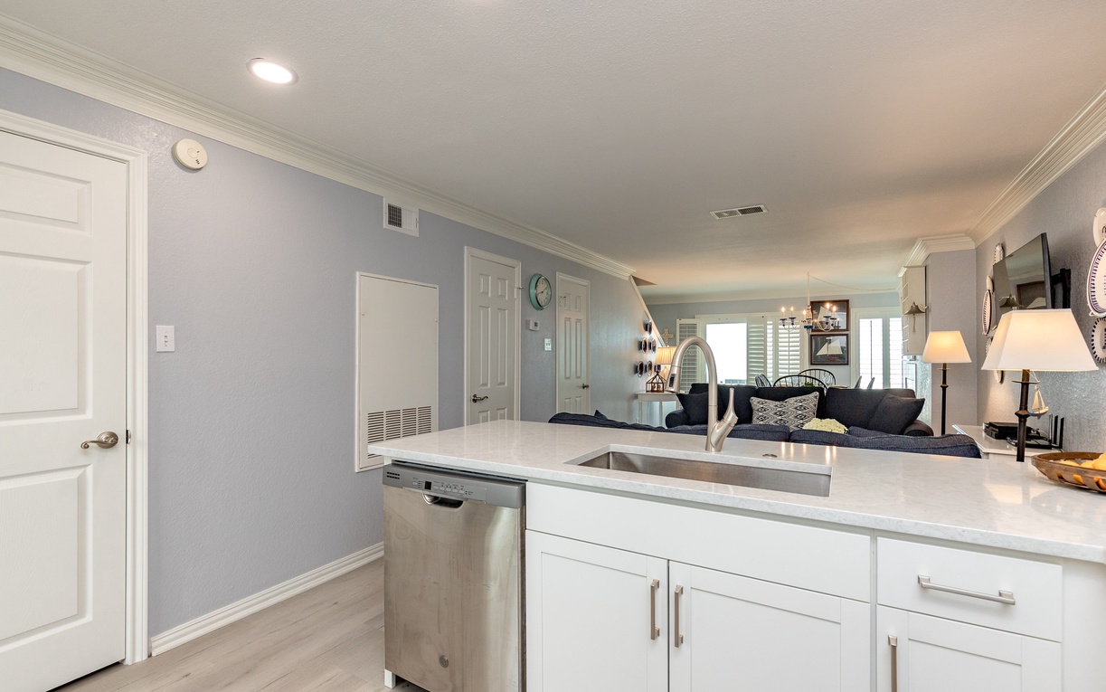 Step into your fully equipped kitchen featuring white cabinets, quartz counters, and stainless steel dishwasher—perfect for preparing meals together.