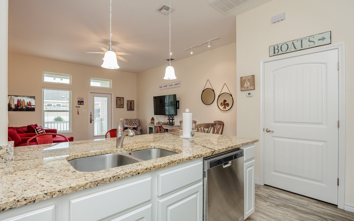 Your fully equipped kitchen features granite counters and stainless appliances, flowing seamlessly into the nautical-themed living space.