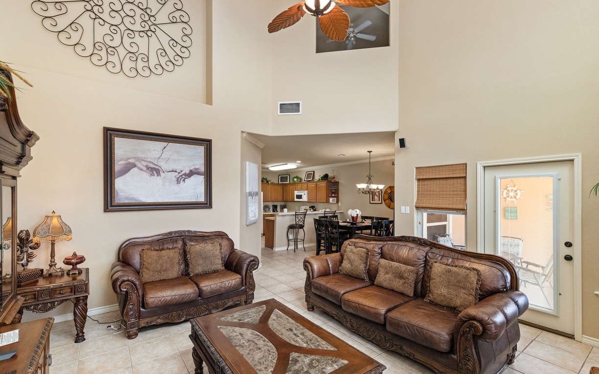Relax in your spacious living room with vaulted ceilings, rich leather sofas, and tropical ceiling fan creating the perfect atmosphere.