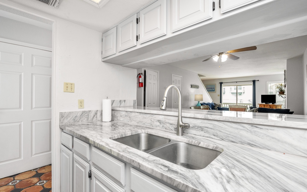 Your bright kitchen features marble countertops, crisp white cabinets, and an open layout connecting to the living area.