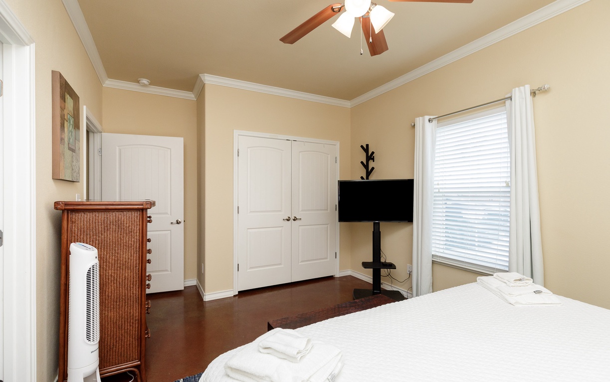Relax in your peaceful primary bedroom with comfortable bedding, ceiling fan, and a king size bed.