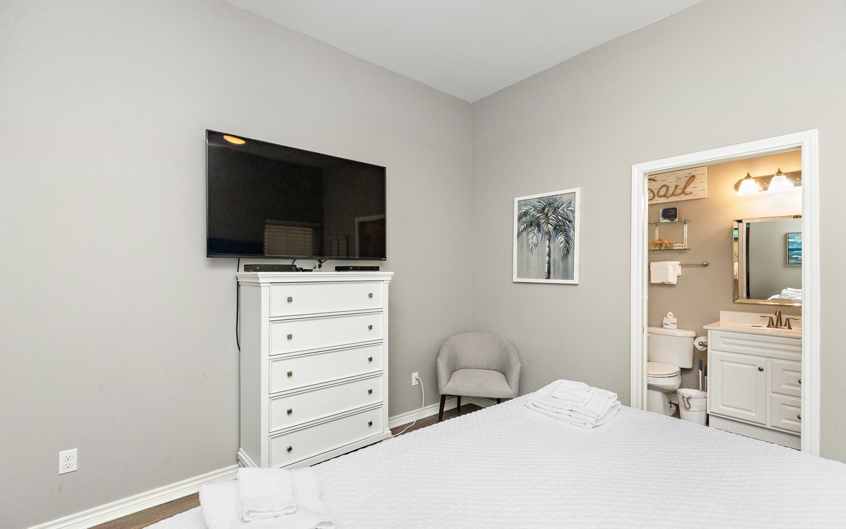 Unwind in your serene bedroom featuring a wall-mounted TV and cozy reading chair, with your private ensuite bathroom just steps away.