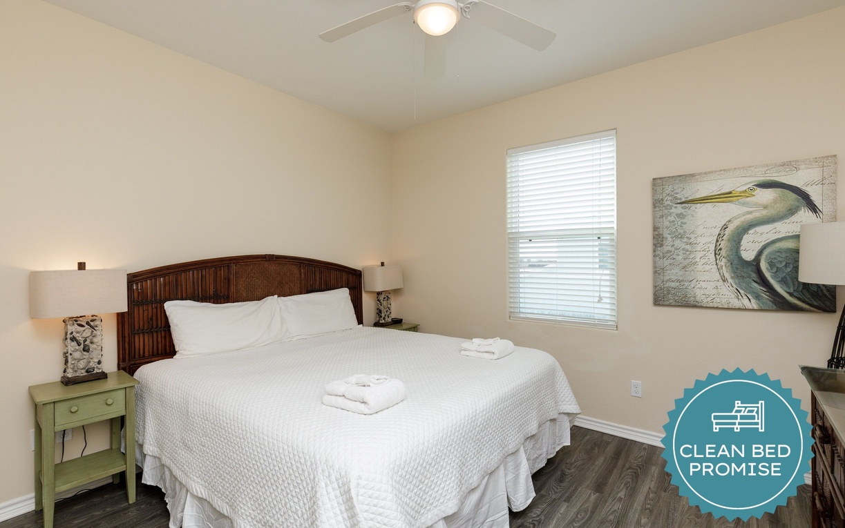 Unwind in your serene bedroom with crisp linens, coastal artwork, and gentle ceiling fan creating the perfect sleep sanctuary.