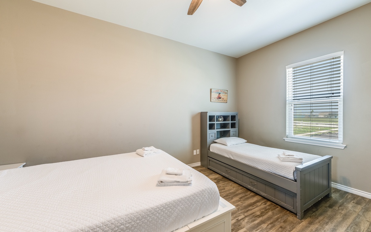 Unwind in your guest bedroom with a queen size bed, a twin beds with twin trundle, soft linens, and natural light streaming through the window.