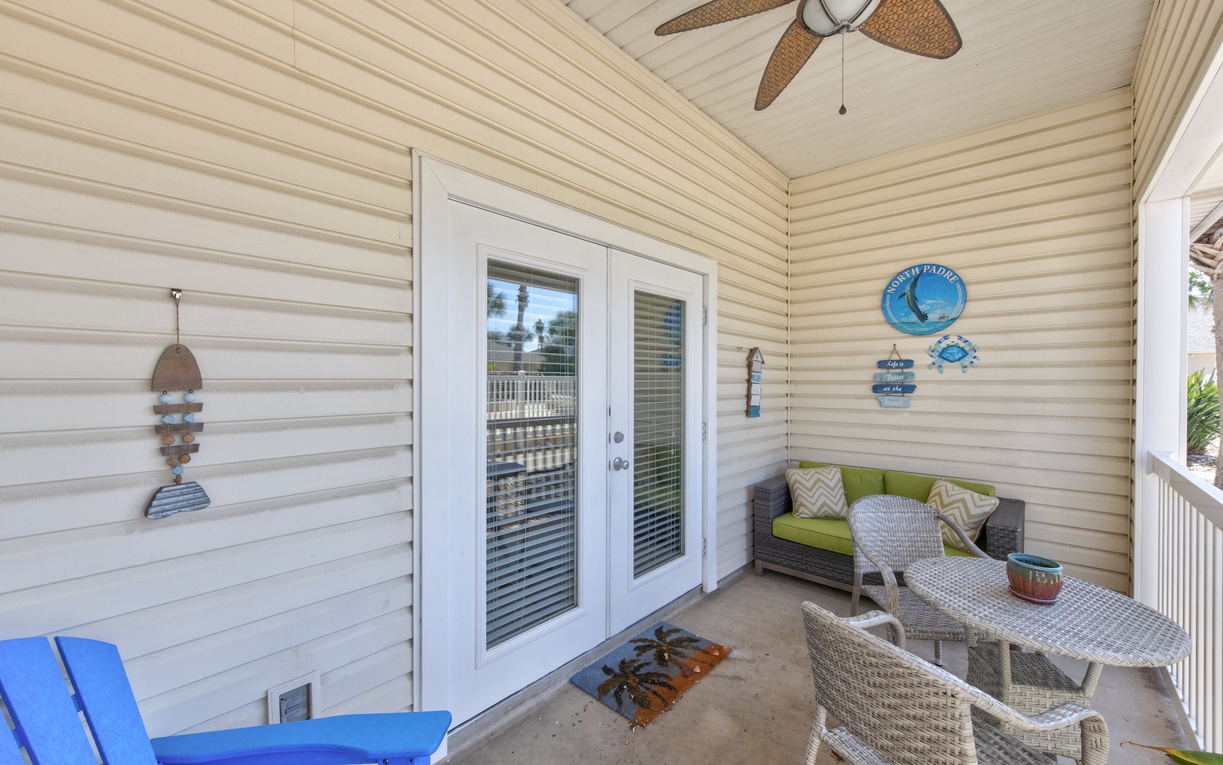 Relax on your private covered balcony with wicker furniture, ceiling fan, and coastal decor creating the perfect retreat.