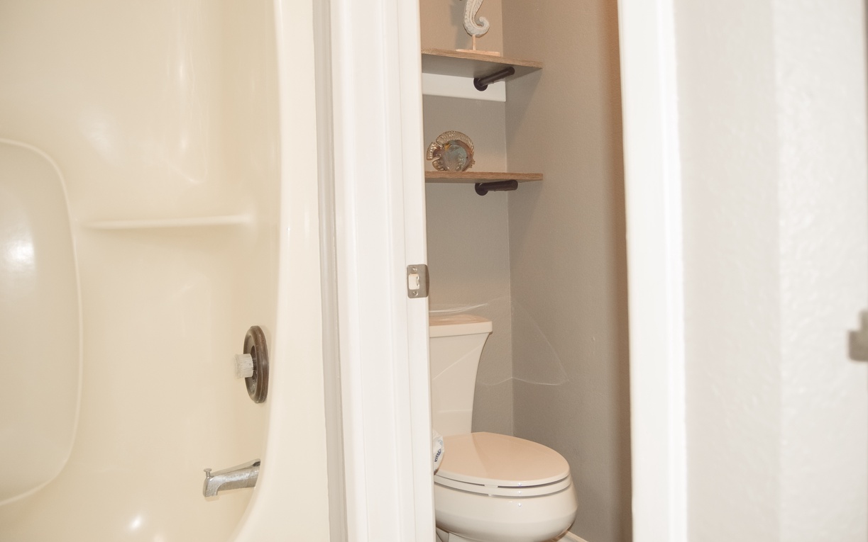Your private bathroom features modern fixtures and thoughtful touches like floating shelves with coastal decor for a serene retreat.