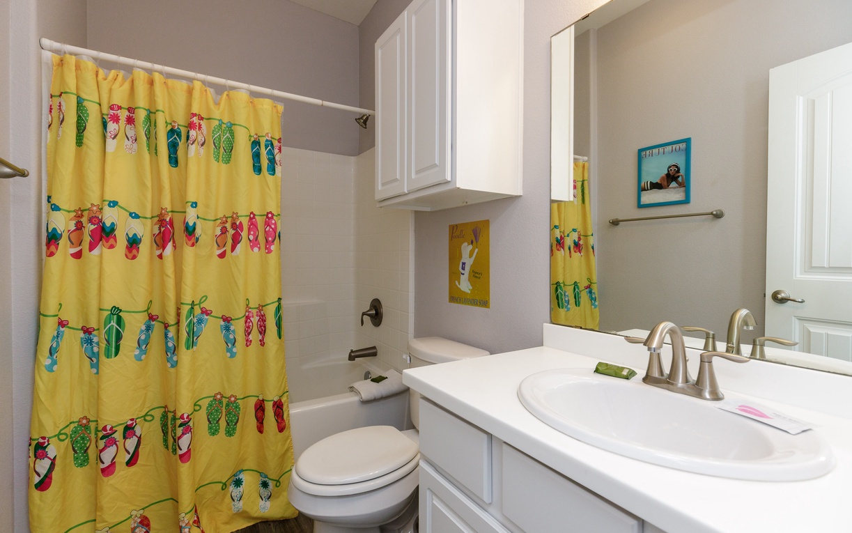 Step into your bright, cheerful bathroom featuring a fun flip-flop themed shower curtain and pristine white vanity with ample storage.