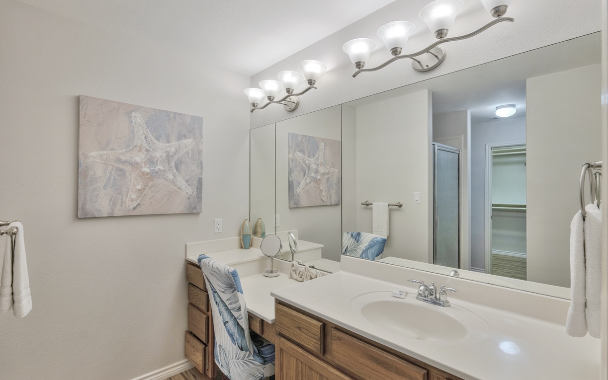 Pamper yourself in this spa-like bathroom with dual vanities, coastal artwork, and excellent lighting for your morning routine.
