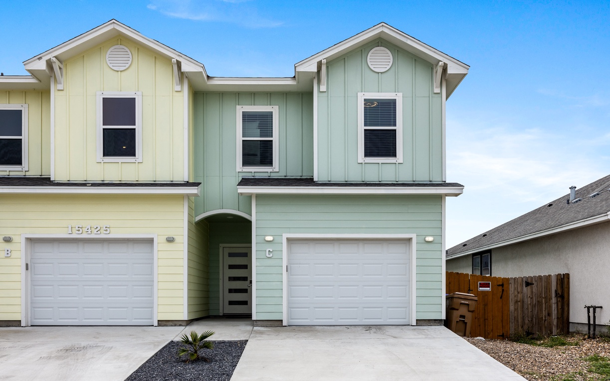 Modern duplex home featuring clean lines, bright coastal colors, and driveway parking in a friendly neighborhood setting.
