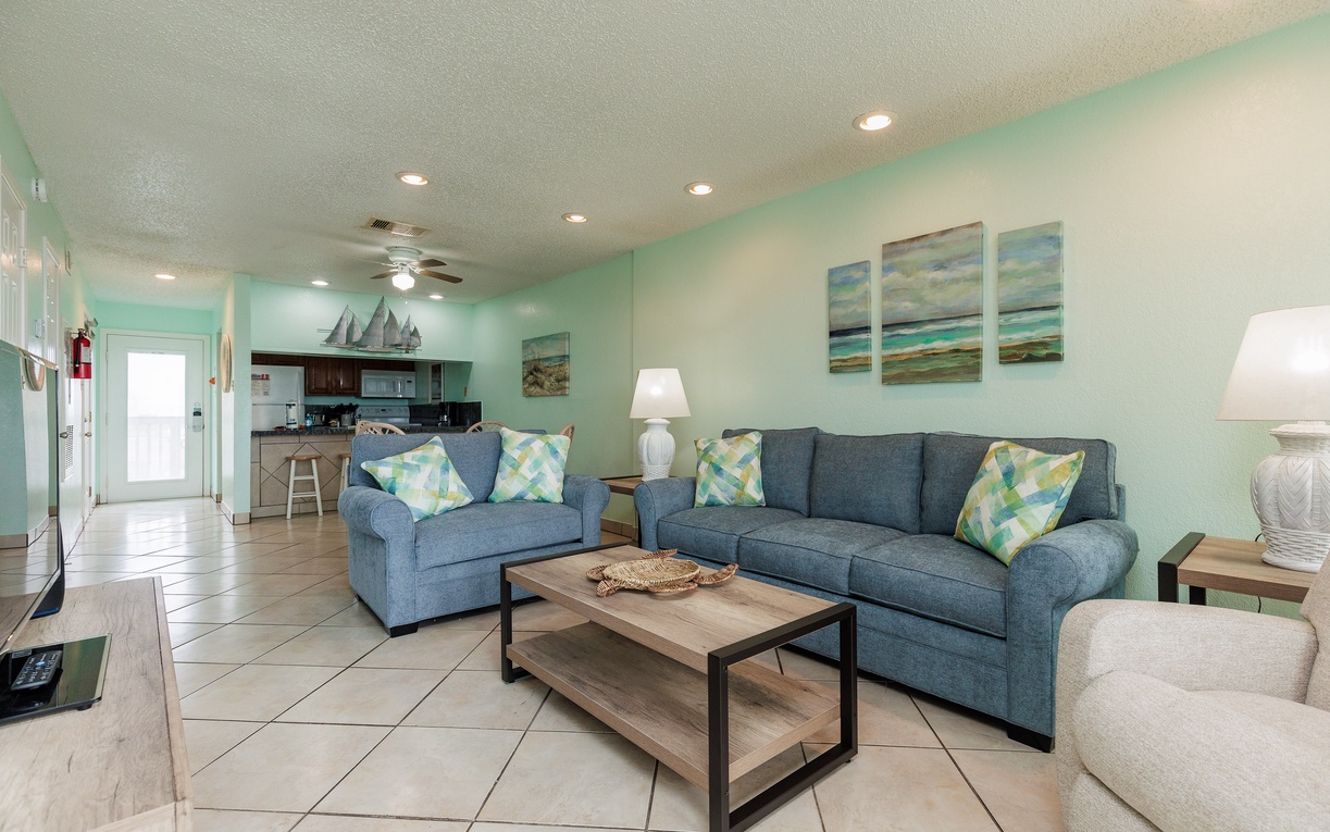 Relax in your coastal living space with ocean-themed decor, comfortable sleeper sofa, and an open kitchen perfect for beachside getaways.