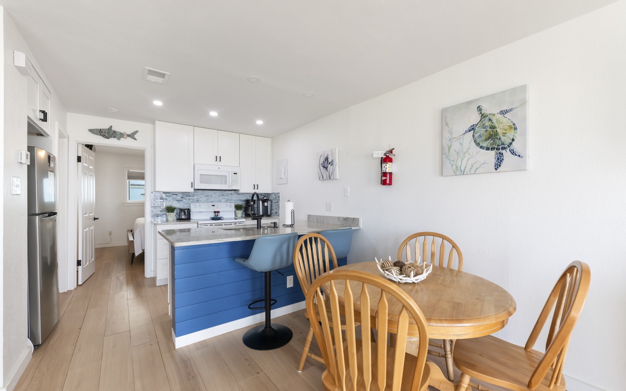 Gather around the inviting dining table with ocean-themed art adorning the walls, then step into your modern kitchen with white cabinetry, bar seating, and everything you need to prepare your favorite meals together.