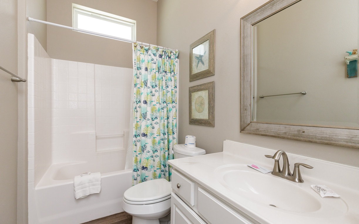 Refresh in your private bathroom featuring a spacious shower-tub combo, clean white surfaces, and cheerful coastal-themed touches.