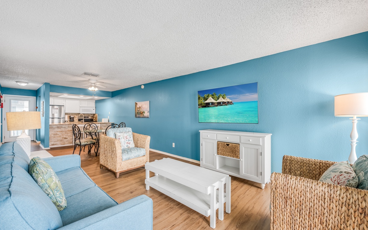 Relax in your bright coastal living room with tropical blue walls, wicker accents, and ocean artwork setting a beachy mood.