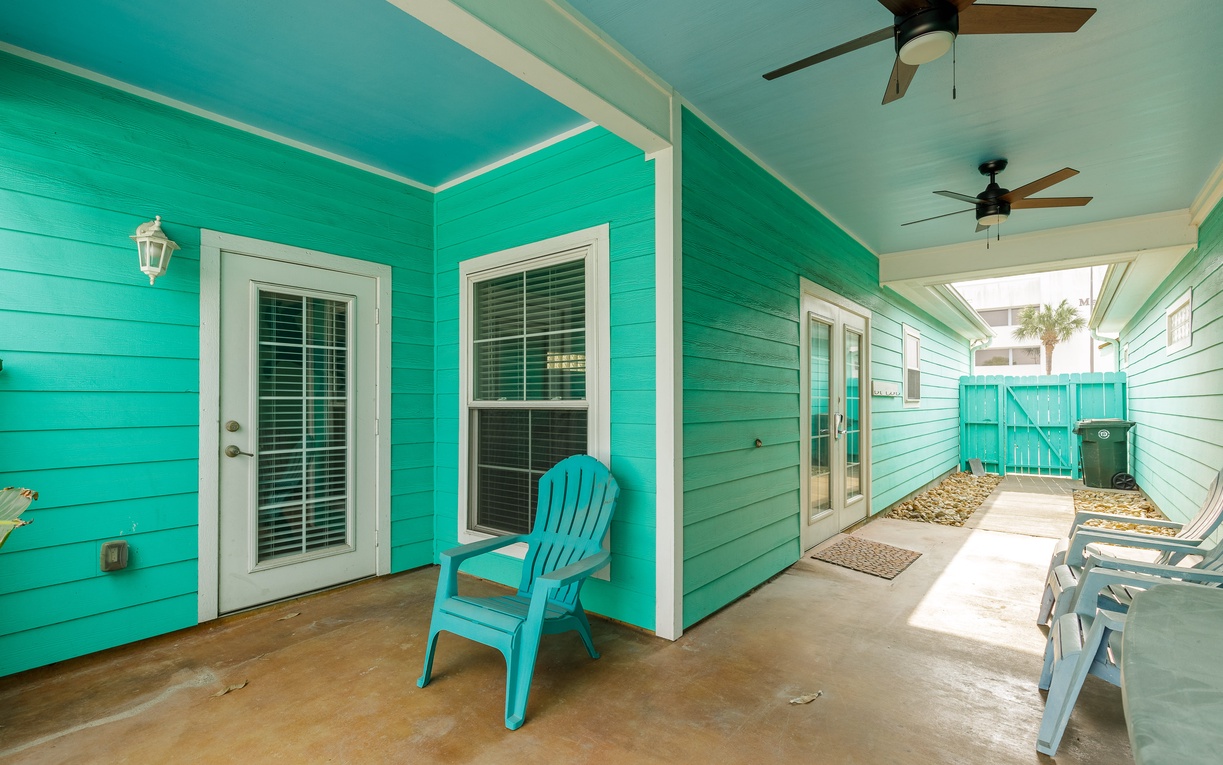 Relax on your private patio with vibrant turquoise walls and comfortable seating, where ceiling fans keep you cool.