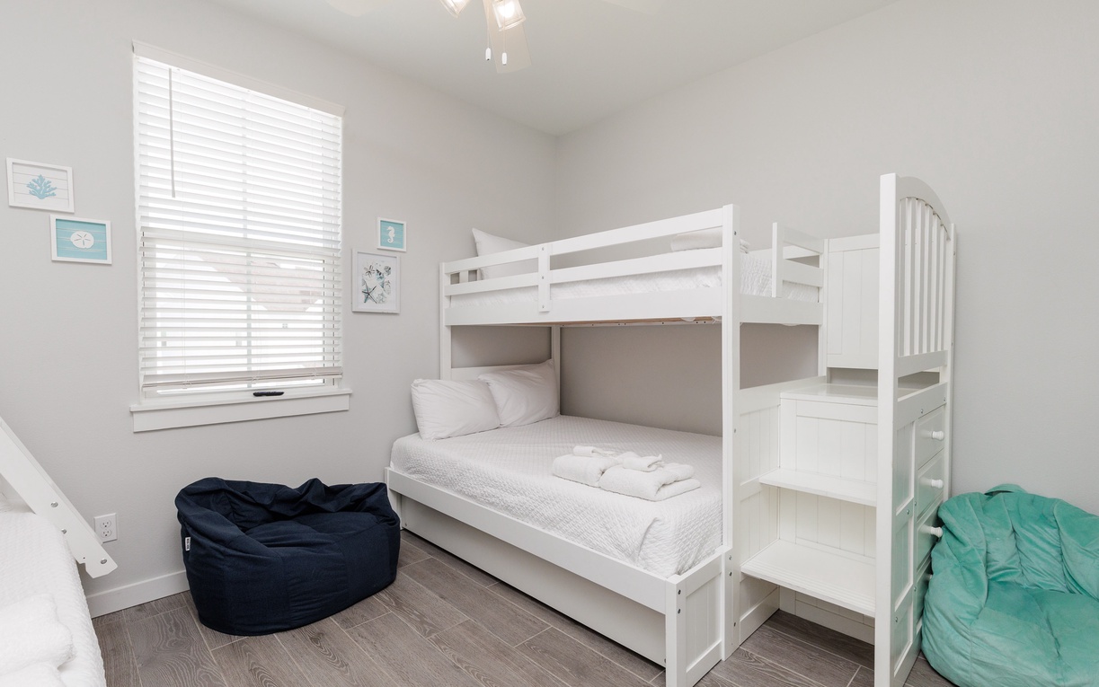 Your kids will love this bright, cheerful bedroom with two sets of twin over full bunk beds, fun bean bag seating, and coastal artwork creating the perfect sleepover atmosphere.