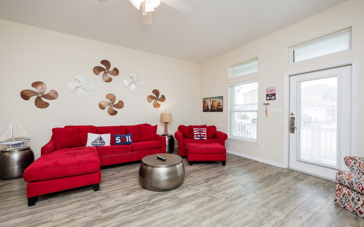 Sink into vibrant red sofas in your nautical-themed living room, where ceiling fans create gentle breezes and balcony doors open to fresh air.