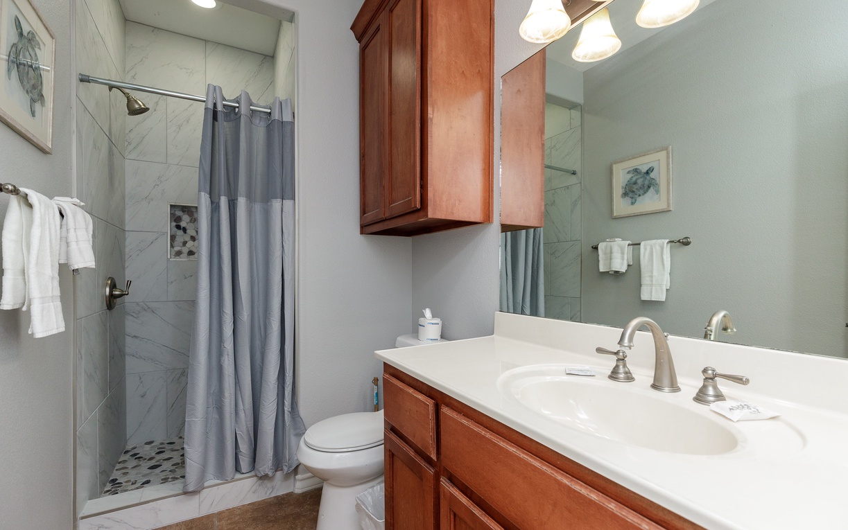Refresh in your private bathroom featuring marble-tiled shower, dual vanity sinks, and warm cherry cabinetry for all your essentials.