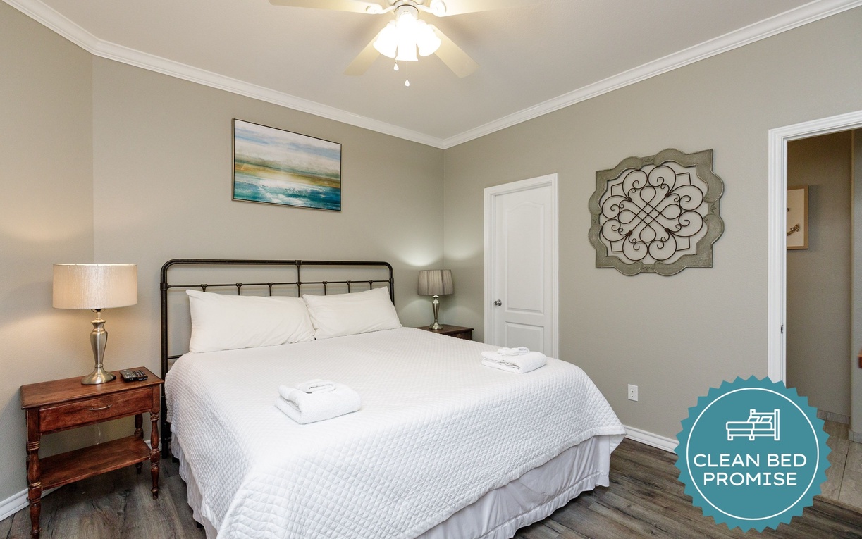 Sink into crisp white linens in your peaceful bedroom, where soft lighting and thoughtful artwork create the perfect retreat.