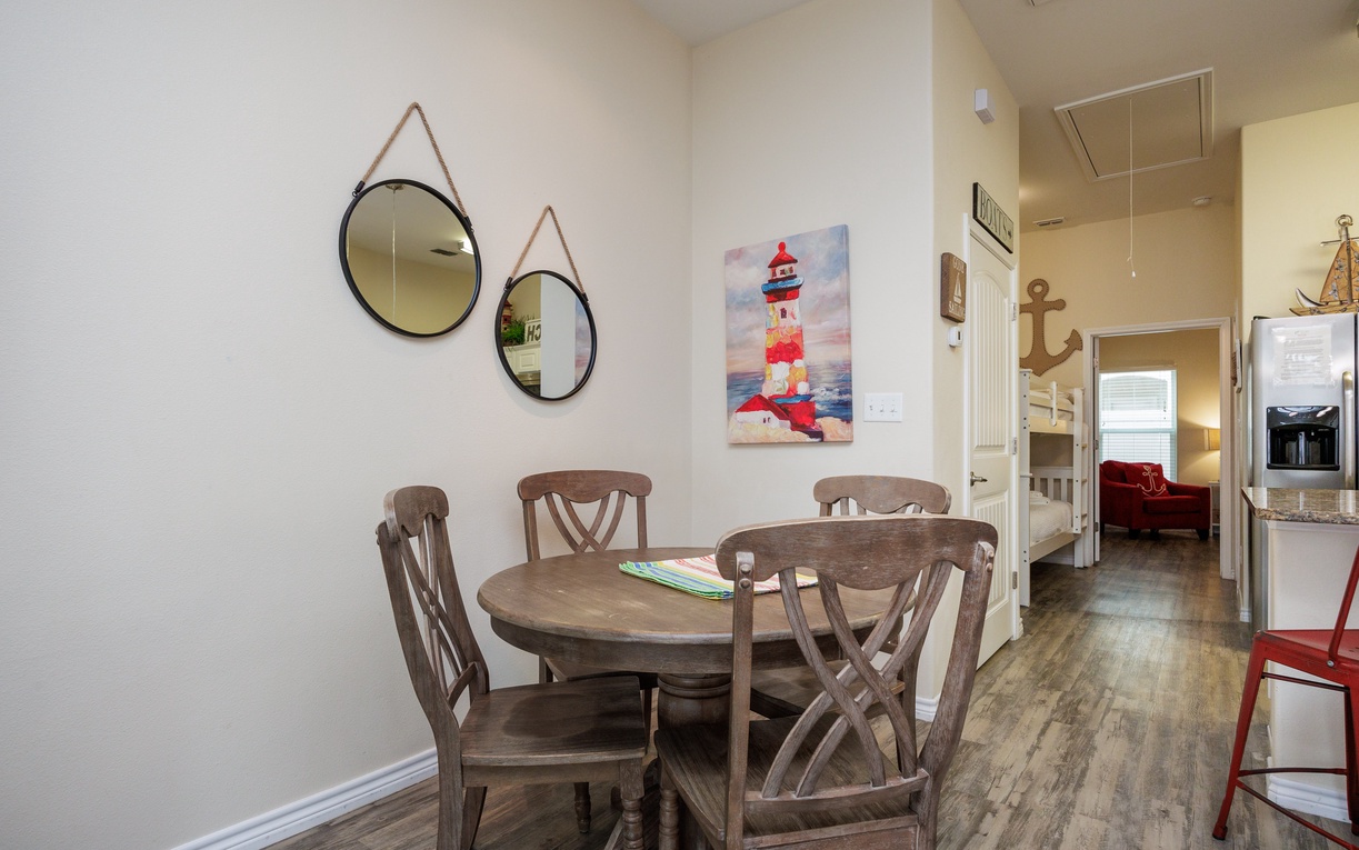 Gather around your charming dining table for meals and conversation, with coastal artwork adding seaside charm to your home away from home.